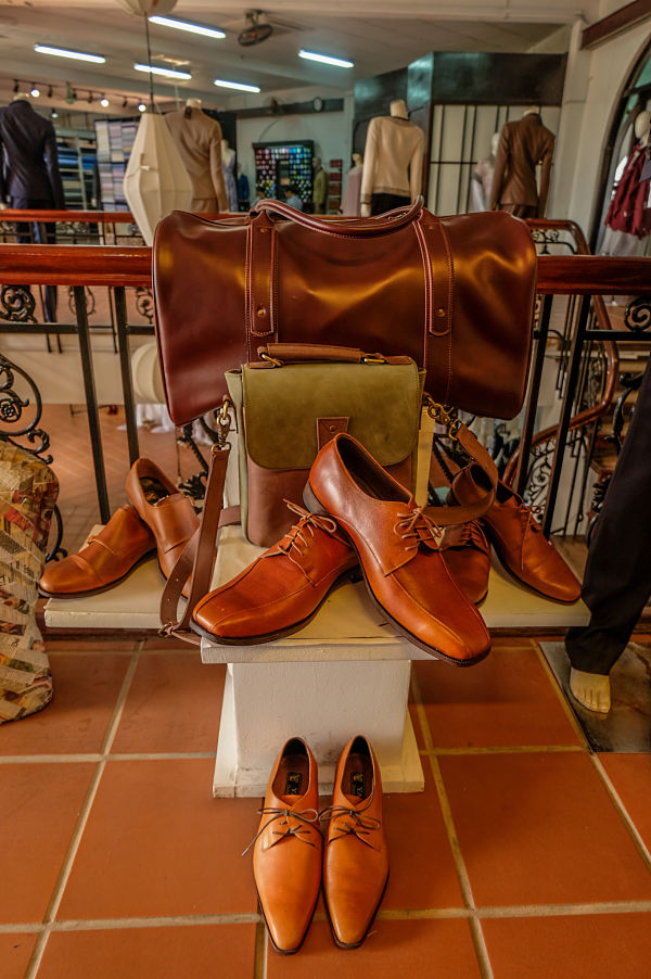 Four pairs of leather tan shoes displayed on and against a white column in Yaly Couture shows the quality of leather shoes you can get made up in Hoi an