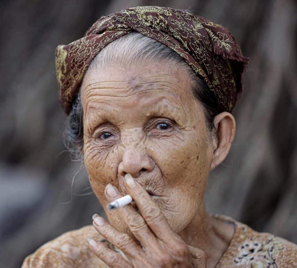 Tips Essentials Top Tips show a wisened old Vietnamese taking a long drag of a cigarette, her wyes deep in thought and concentration