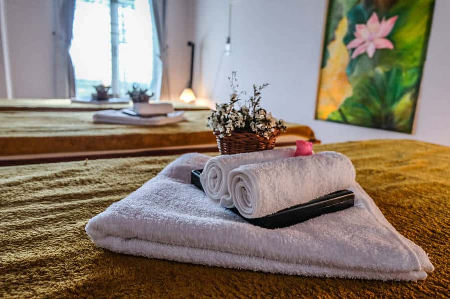 ma spa hoi an, a bed with white towels and flowers