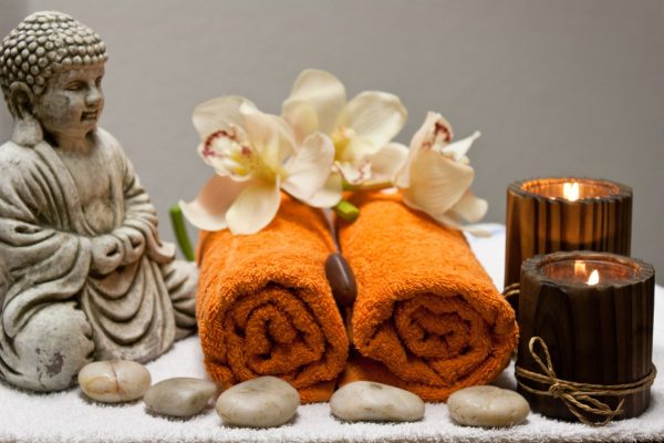 Decorative buddhas flank orange folded hand towels adorned atop with frangipanis show the class of some Hoi An Massage and Spas