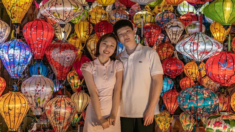 Couple standing amongst lantern stall lanterns at Hoi An Night Market