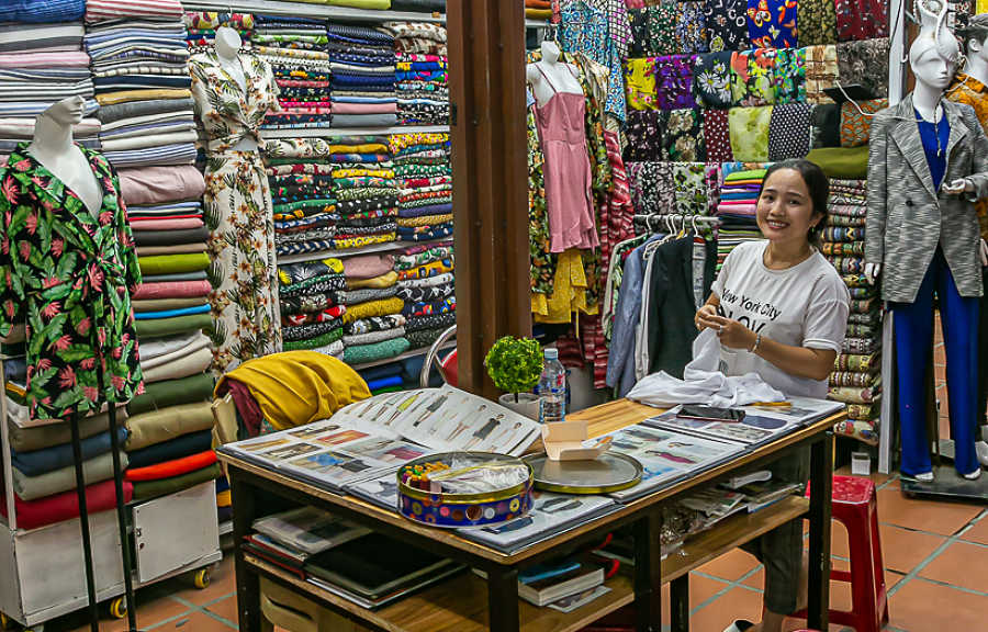 Sewing Bee owner smiles out from her tailor shop in Hoi An's Cloth Market.  She is one of the best cheap end tailors in Hoi An.