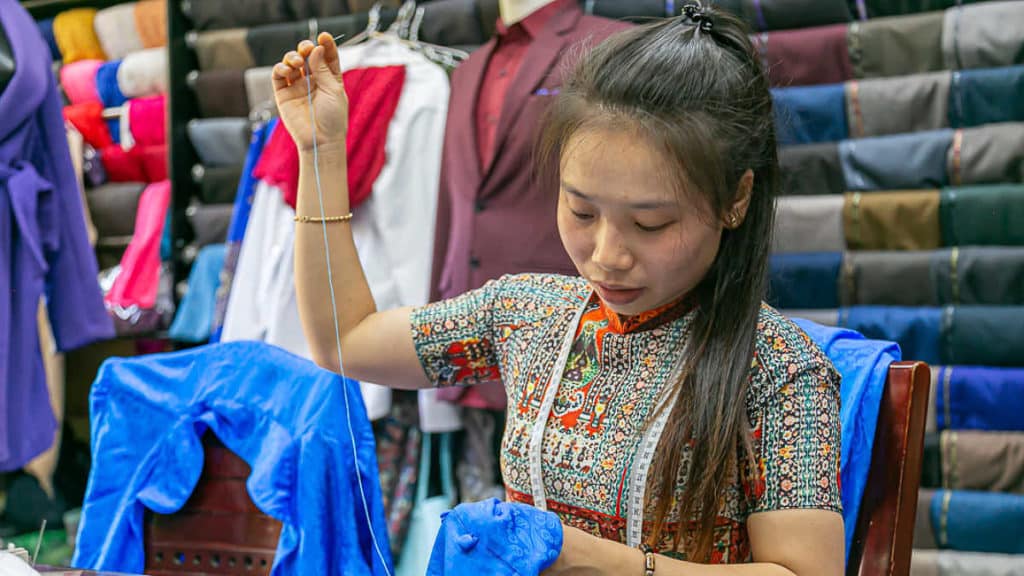 Vietnamese seamstress sewing garments in Hoi An Cloth Market