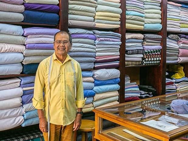 Mr Xe stands infront of his massive selection of shirt material.  One of the best tailors for suits and shirts in Hoi An
