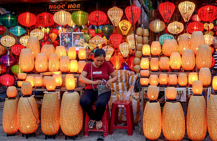 Nightmarket-seller- surrounded-by-colorful-lanterns-of-all-shapes-and-sizes hoping to pull in tourists wondering what to buy in Vietnam