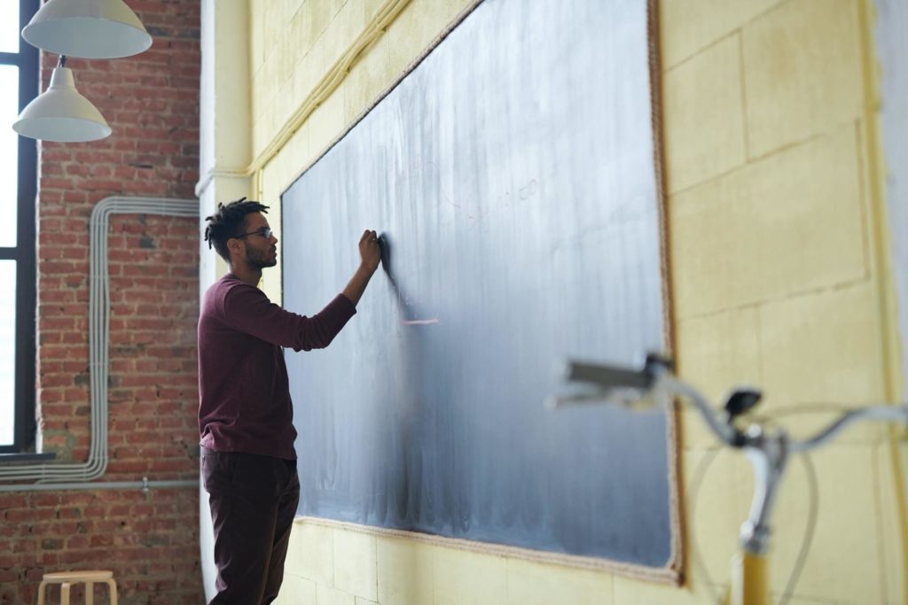 Image of a teacher writing on a blackboard