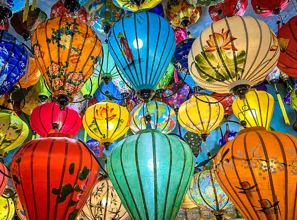 Bright colored silk lanterns of all shapes and sizes hang from a souvenir shop ceiling in Hoi An