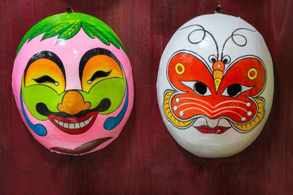 Two brightly colored hand made masks show what you can make at the Timing Shop Workshops
