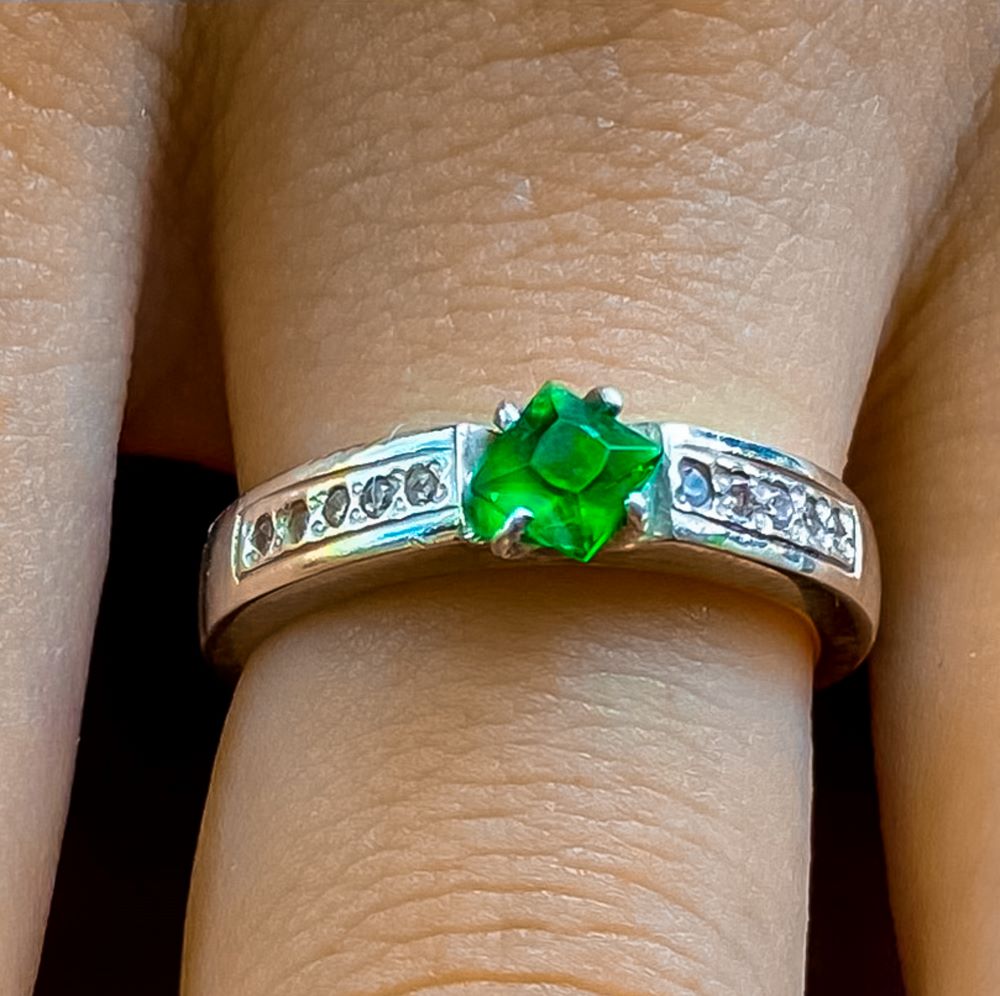 Close up of silver ring with green stone centre piece on finger shows how you can custom your own jewellery at Ruby Jewellery Hoi An.