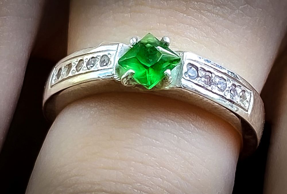 Close up of silver ring with green stone centre piece on finger shows how you can custom your own jewellery at Ruby Jewellery Hoi An.