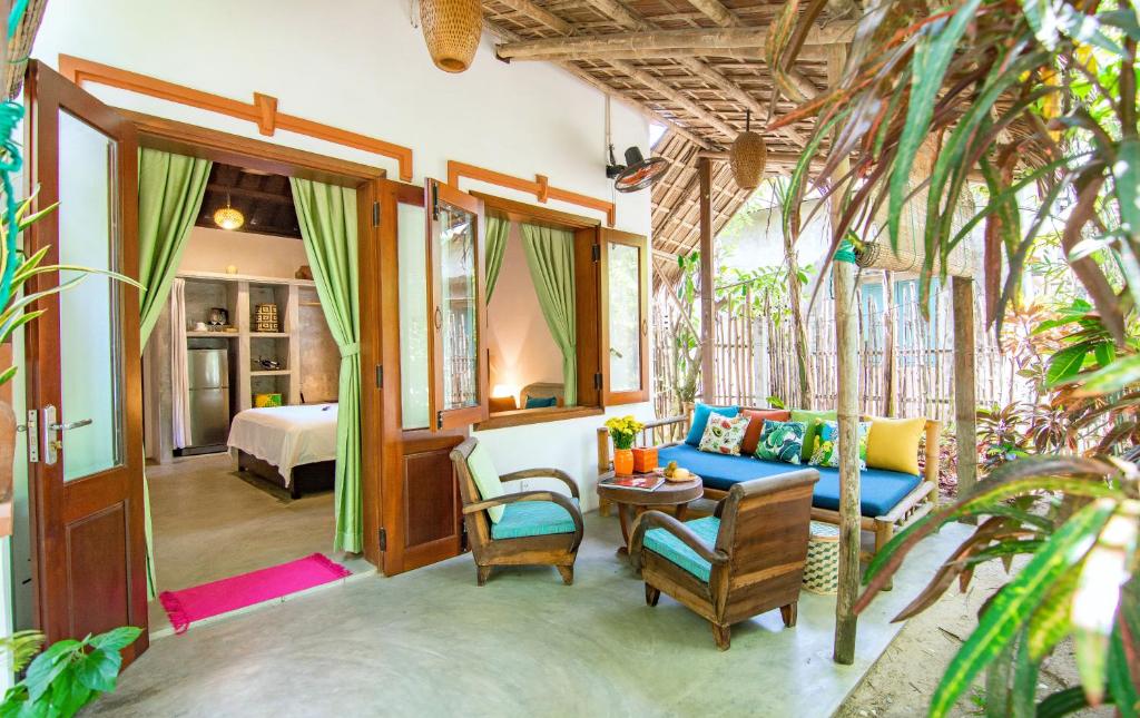 An Bang Flower House Airbnb in An Bang Beach Hoi An with tropical garden patio, wooden seating, open doors, and cozy bedroom inside